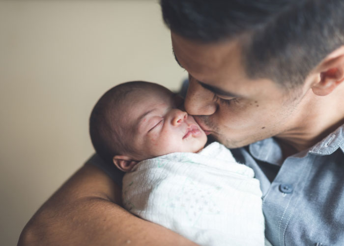 Dad holding and kissing baby