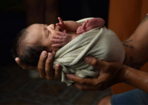Father hands holding swaddled infant